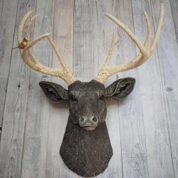 Faux taxidermy deer head painted chestnut brown with cream and gold accenting. Cream antlers with gold antlers, a brass bird rests atop one of the antlers.