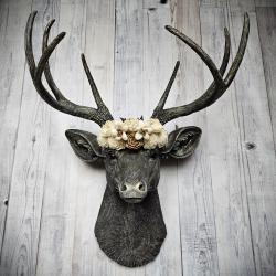 faux taxidermy deer head, painted chestnut brown with gold and antique white accents. The antlers have been painted in the same color combination. A floral crown made of cream and natural bark sola flowers rests atop the deers head.