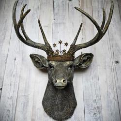 faux taxidermy deer head that's been painted chestnut brown with gold and antique white accents, the antlers are painted in the same color combination. A vintage bronze Santos metal crown with rhinestones accents the top of the deers head.