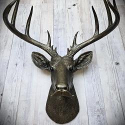 Faux taxidermy deer head sporting a moustache, entire piece is painted rubbed bronze with antique gold accenting. 