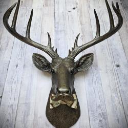 Faux taxidermy deer head sporting a moustache, entire piece is painted rubbed bronze with antique gold accenting. The deer has fabric bow tie on it's neck, different fabrics available.