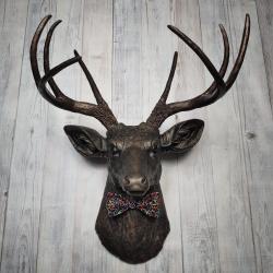 Faux taxidermy deer head, painted rubbed bronze with dark copper accenting on the head, antlers are dark copper. Removable bow tie, fabric is black with multi colored sprinkles.