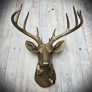Faux taxidermy deer head with smoking pipe and bow tie, painted antique gold with dark bronze accents.