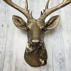 Faux taxidermy deer head with smoking pipe and bow tie, painted antique gold with dark bronze accents.