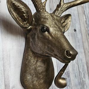 Faux taxidermy deer head wall mount with smoking pipe, painted antique gold with dark bronze accenting.