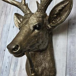 Faux taxidermy deer head wall mount with smoking pipe, painted antique gold with dark bronze accenting.