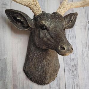 Faux taxidermy deer head painted chestnut brown with cream and gold accenting. Cream antlers with gold antlers, a brass bird rests atop one of the antlers.