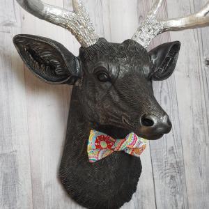 Faux taxidermy deer head painted black with silver antlers and a removable bright multi colored bow tie