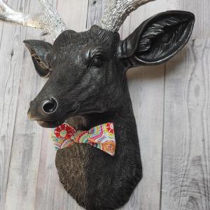 Faux taxidermy deer head painted black with silver antlers and a removable bright multi colored bow tie
