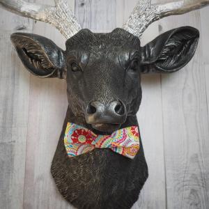 Faux taxidermy deer head painted black with silver antlers and a removable bright multi colored bow tie