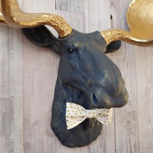 Faux taxidermy moose head painted midnight blue with metallic gold antlers. A white and gold polka dot bow tie accents the neck of the moose.