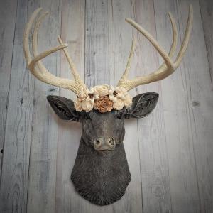 Faux taxidermy deer head, painted chestnut brown with antique white and gold accenting. Antlers are antique white with gold and chestnut brown accenting. A cream floral crown rests atop the deers head.