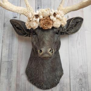 Faux taxidermy deer head, painted chestnut brown with antique white and gold accenting. Antlers are antique white with gold and chestnut brown accenting. A cream floral crown rests atop the deers head.