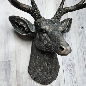 Faux taxidermy deer head wall mount. The head and antlers are black with dark copper accents. The deers head has additional accents in antique white, the eyes are black.