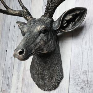 Faux taxidermy deer head wall mount. The head and antlers are black with dark copper accents. The deers head has additional accents in antique white, the eyes are black.