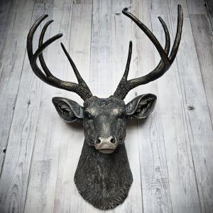 Faux taxidermy deer head wall mount. The head and antlers are black with dark copper accents. The deers head has additional accents in antique white, the eyes are black.
