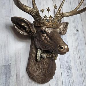 Faux taxidermy deer head wall mount with crown and bow tie.