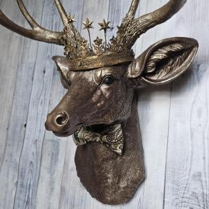 Faux taxidermy deer head wall mount with crown and bow tie.