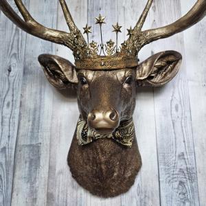 Faux taxidermy deer head wall mount with crown and bow tie.