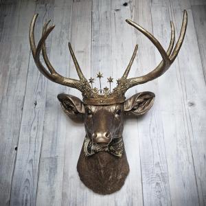 Faux taxidermy deer head wall mount with crown and bow tie.