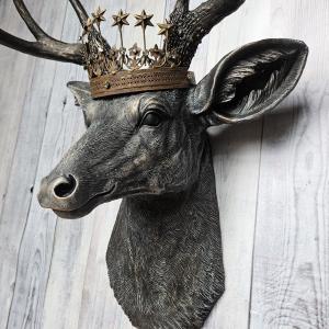 Faux taxidermy deer head wall mount. The head and antlers are black with dark copper accents. The deers head has additional accents in antique white, the eyes are black.A rustic vintage inspired star Santos crown sites atop the deers head