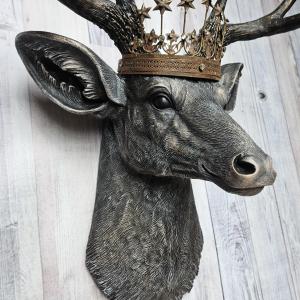 Faux taxidermy deer head wall mount. The head and antlers are black with dark copper accents. The deers head has additional accents in antique white, the eyes are black.A rustic vintage inspired star Santos crown sites atop the deers head