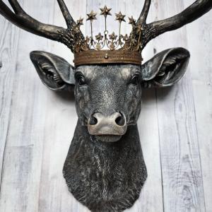 Faux taxidermy deer head wall mount. The head and antlers are black with dark copper accents. The deers head has additional accents in antique white, the eyes are black.A rustic vintage inspired star Santos crown sites atop the deers head