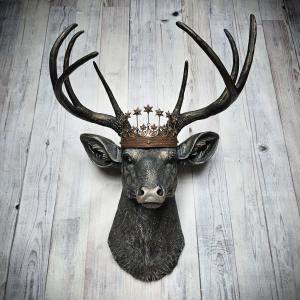 Faux taxidermy deer head wall mount. The head and antlers are black with dark copper accents. The deers head has additional accents in antique white, the eyes are black.A rustic vintage inspired star Santos crown sites atop the deers head.
