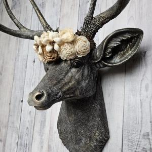 faux taxidermy deer head, painted chestnut brown with gold and antique white accents. The antlers have been painted in the same color combination. A floral crown made of cream and natural bark sola flowers rests atop the deers head.