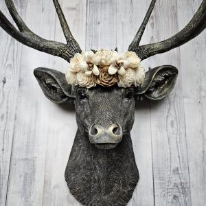faux taxidermy deer head, painted chestnut brown with gold and antique white accents. The antlers have been painted in the same color combination. A floral crown made of cream and natural bark sola flowers rests atop the deers head.