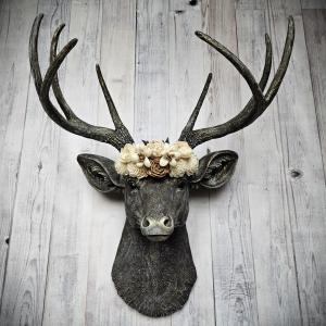 faux taxidermy deer head, painted chestnut brown with gold and antique white accents. The antlers have been painted in the same color combination. A floral crown made of cream and natural bark sola flowers rests atop the deers head.