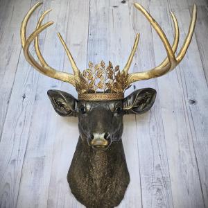 Faux taxidermy deer head wall mount, painted rubbed bronze with gold antlers and gold accents. A metal leaf work gold crown rests atop the deers head.