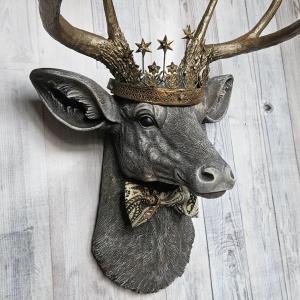 Faux taxidermy deer head wall mount with crown and bow tie.