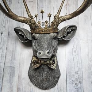 Faux taxidermy deer head wall mount with crown and bow tie.