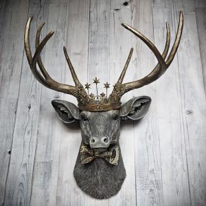 Faux taxidermy deer head wall mount with crown and bow tie.