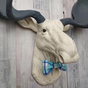 Antique white moose head with slate grey antlers and a blue plaid bow tie