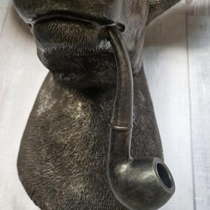Rubbed bronze faux taxidermy deer head with gold accents. A smoking pipe extends from the deers mouth