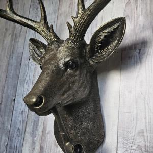 Rubbed bronze faux taxidermy deer head with gold accents. A smoking pipe extends from the deers mouth