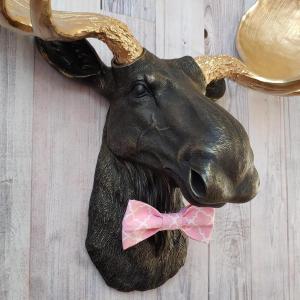Faux taxidermy moose head, head is painted black with gold accents, antlers painted metallic gold, a pink quatrefoil bow tie accents the neck of the moose