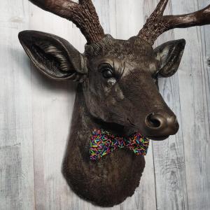 Faux taxidermy deer head, painted rubbed bronze with dark copper accenting on the head, antlers are dark copper. Removable bow tie, fabric is black with multi colored sprinkles.