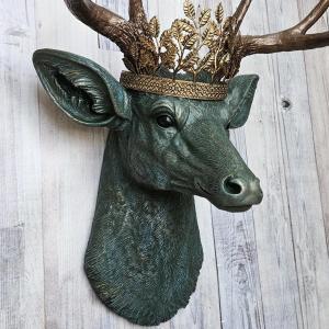 Faux taxidermy deer head wall mount, head is painted verdigris with antique gold antlers. A metal leaf crown rests atop the deers head