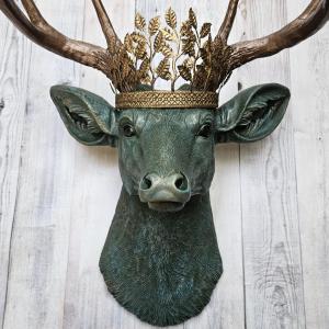 Faux taxidermy deer head wall mount, head is painted verdigris with antique gold antlers. A metal leaf crown rests atop the deers head