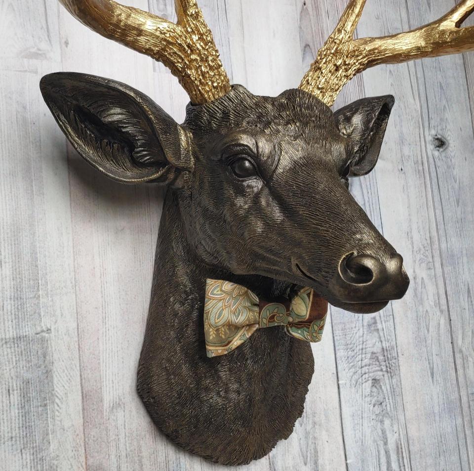 Faux taxidermy deer head painted rubbed bronze with gold antlers and a removable brown multi colored bow tie