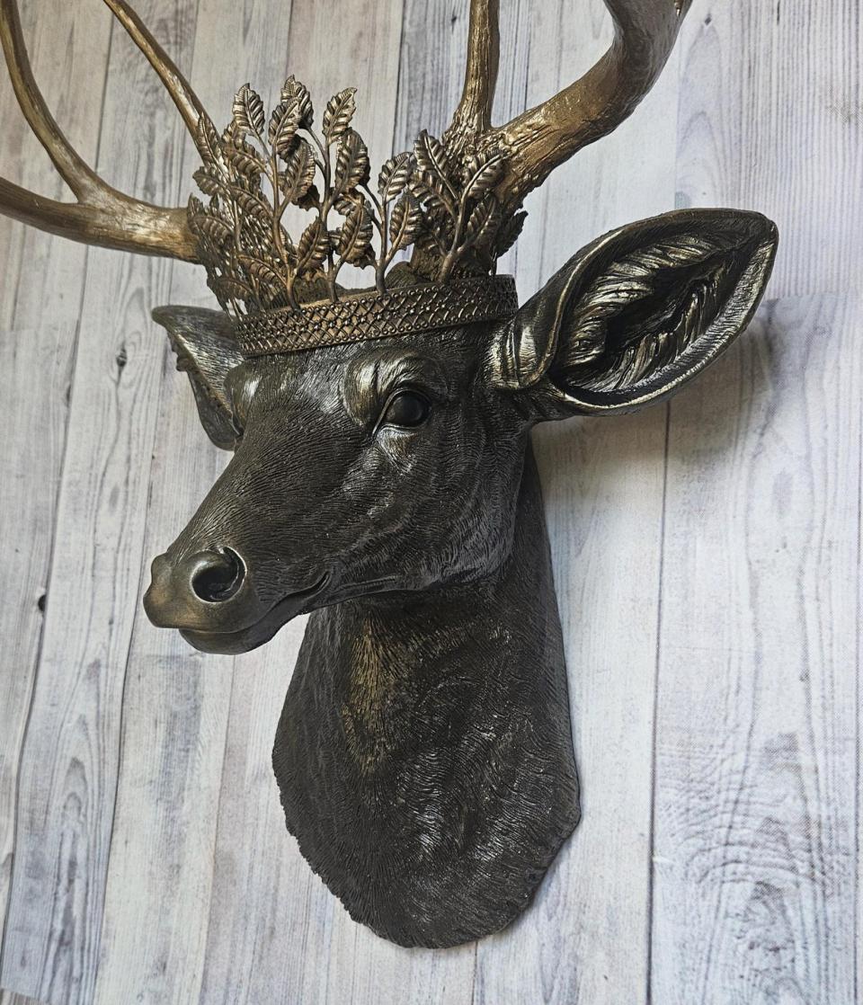 faux taxidermy deer head wall mount in black with gold accenting and gold antler. A gold metal work crown rests atop the deers head.