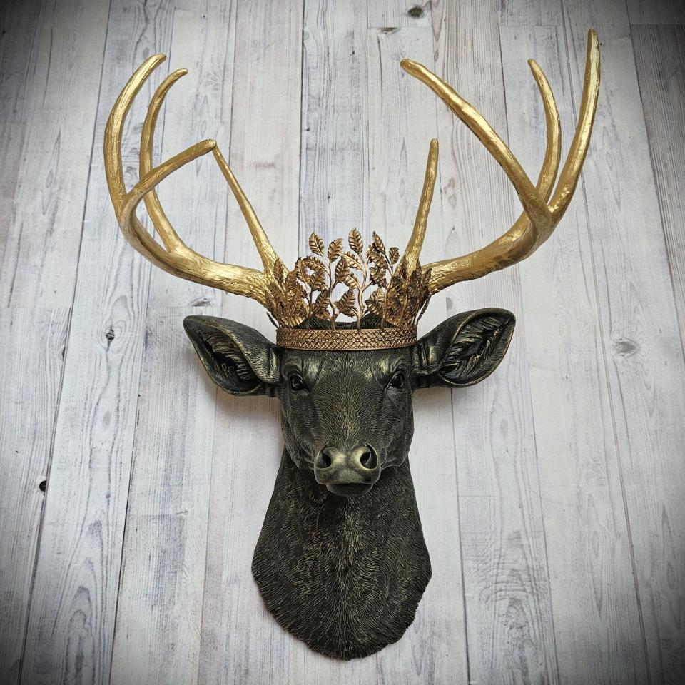 faux taxidermy deer head wall mount in black with gold accenting and gold antler. A gold metal work crown rests atop the deers head.