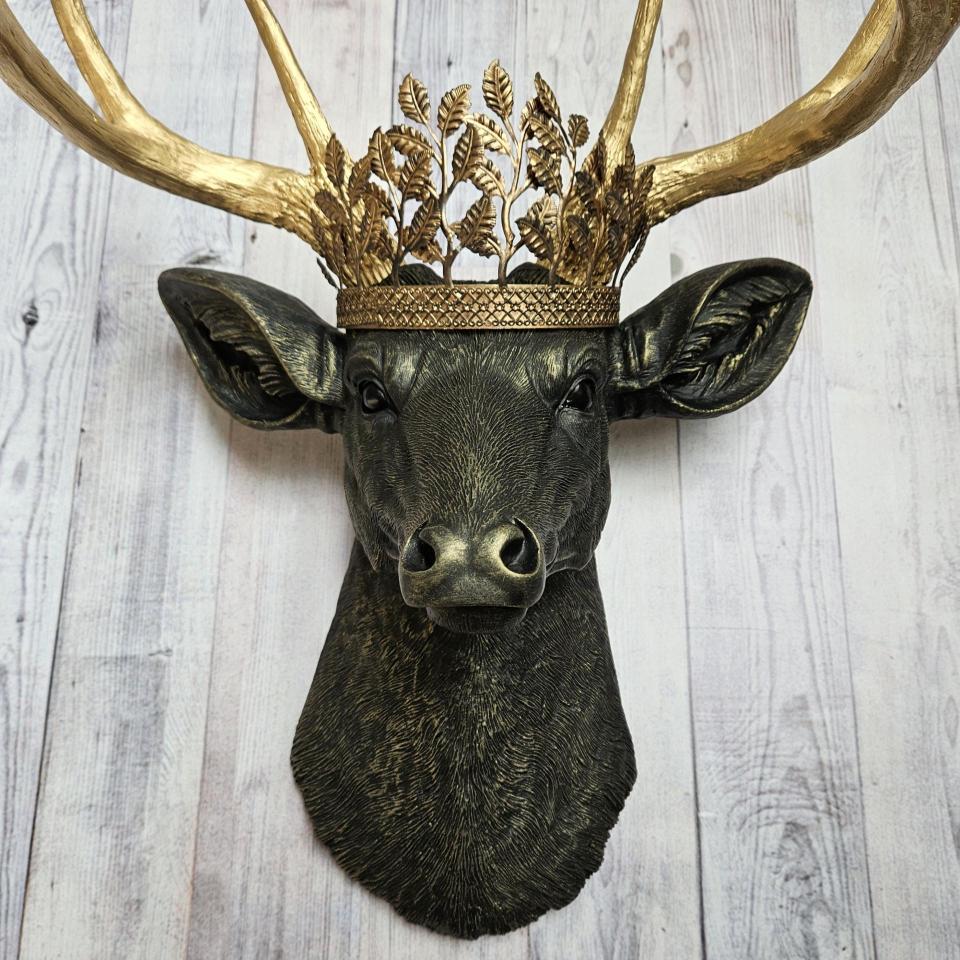 faux taxidermy deer head wall mount in black with gold accenting and gold antler. A gold metal work crown rests atop the deers head.