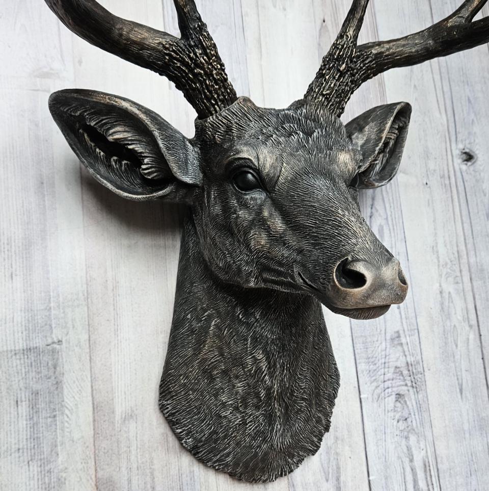 Faux taxidermy deer head wall mount. The head and antlers are black with dark copper accents. The deers head has additional accents in antique white, the eyes are black.