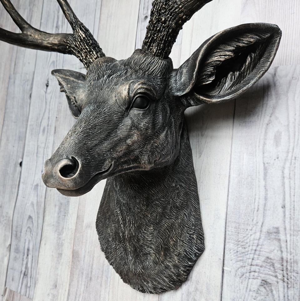 Faux taxidermy deer head wall mount. The head and antlers are black with dark copper accents. The deers head has additional accents in antique white, the eyes are black.