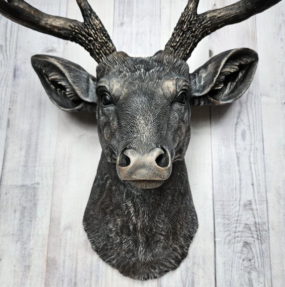 Faux taxidermy deer head wall mount. The head and antlers are black with dark copper accents. The deers head has additional accents in antique white, the eyes are black.