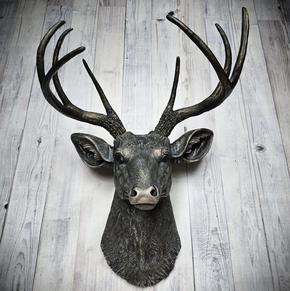 Faux taxidermy deer head wall mount. The head and antlers are black with dark copper accents. The deers head has additional accents in antique white, the eyes are black.